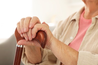 Photo of Senior woman with walking cane indoors, closeup