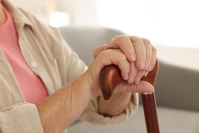 Senior woman with walking cane indoors, closeup