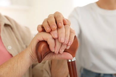 Caregiver supporting senior woman at home, closeup