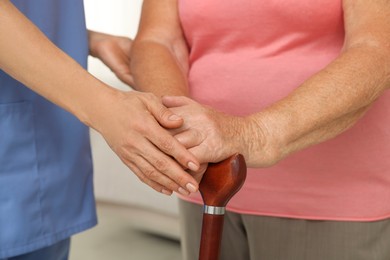 Photo of Healthcare worker supporting senior patient indoors, closeup