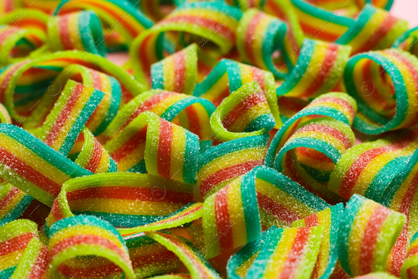 Photo of Tasty rainbow sour belts as background, closeup