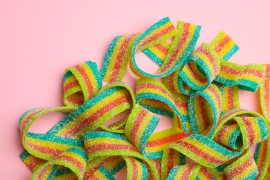 Photo of Tasty rainbow sour belts on pink background, top view