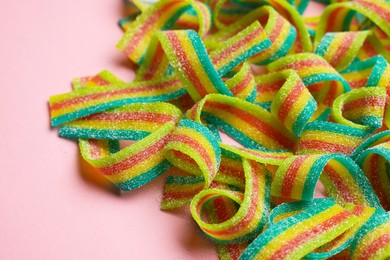 Photo of Tasty rainbow sour belts on pink background, closeup