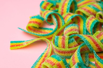 Photo of Tasty rainbow sour belts on pink background, closeup