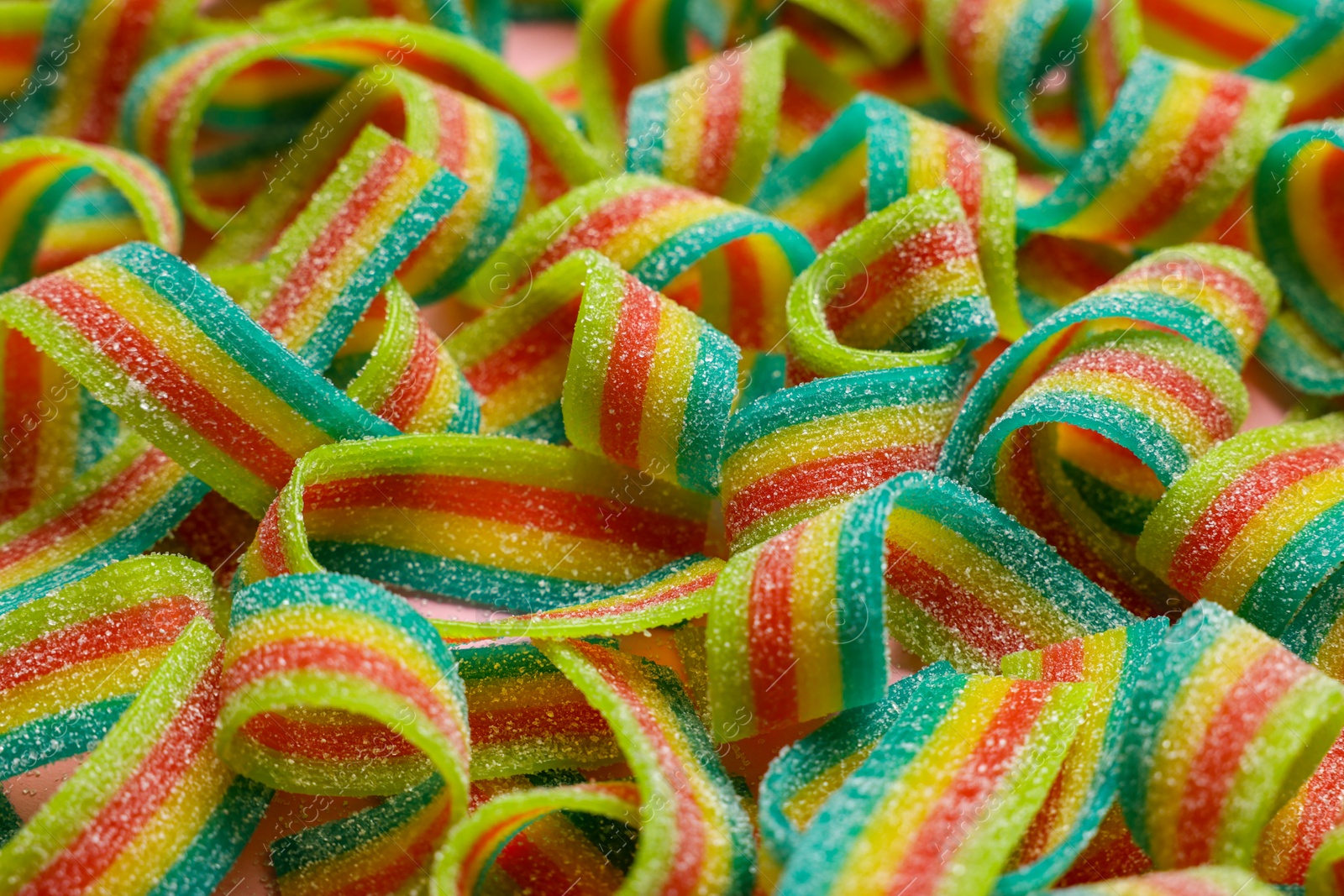 Photo of Tasty rainbow sour belts on pink background, closeup