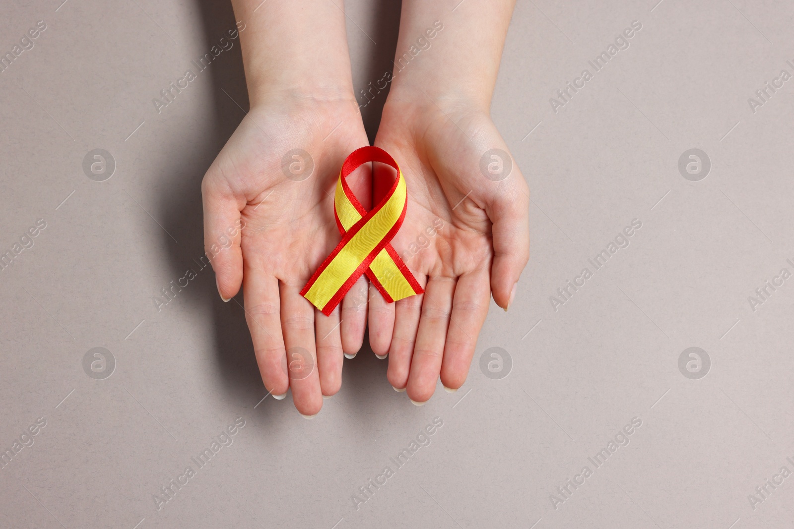 Photo of Woman with yellow and red ribbon on grey background, top view. Hepatitis C awareness