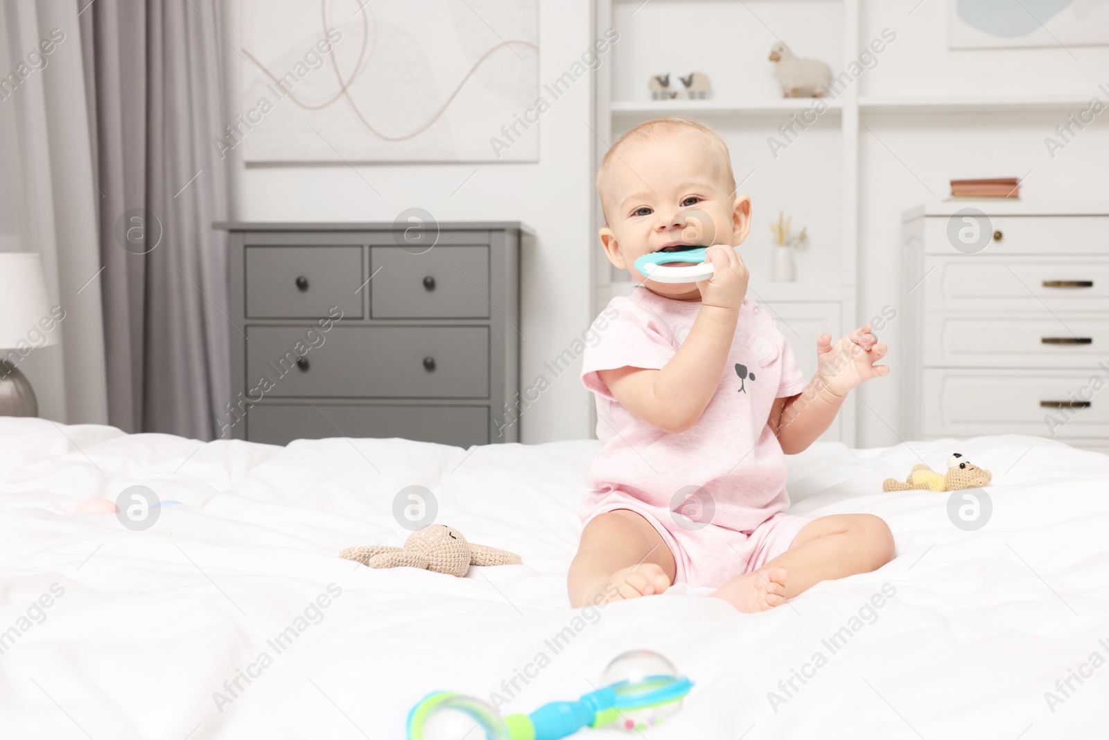 Photo of Cute little baby with rattles on bed indoors