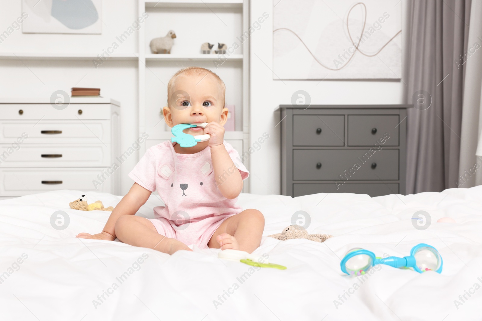 Photo of Cute little baby with rattles on bed indoors