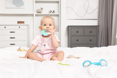 Photo of Cute little baby with rattles on bed indoors