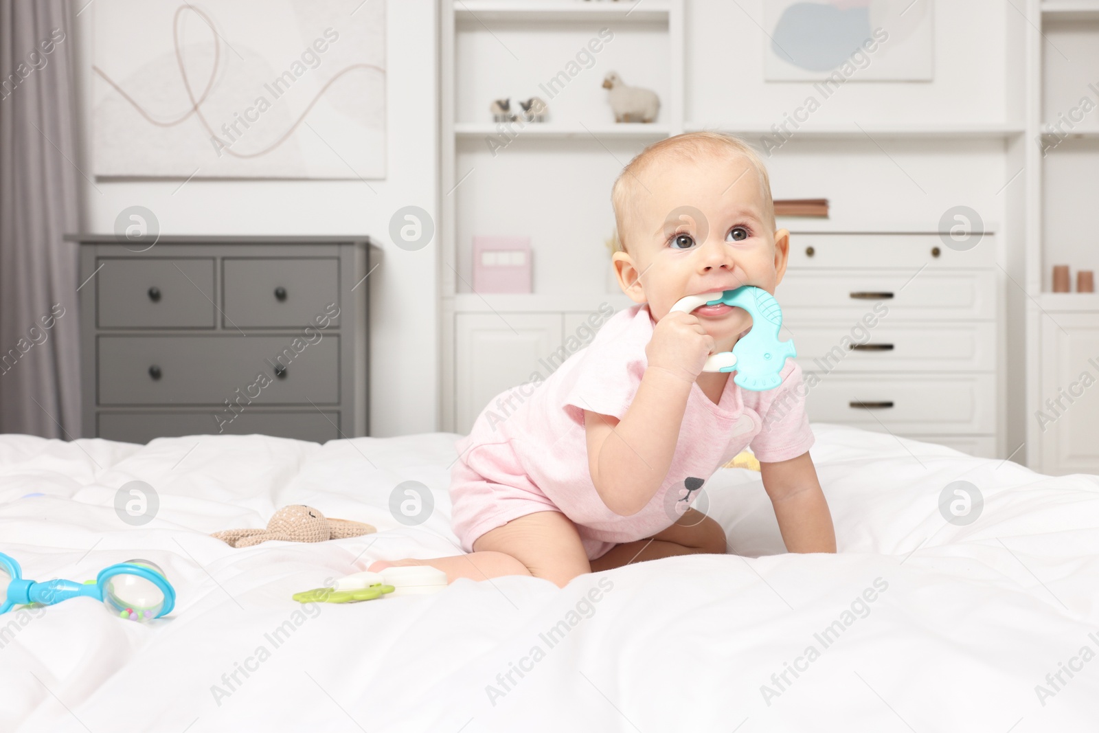 Photo of Cute little baby with rattles on bed indoors