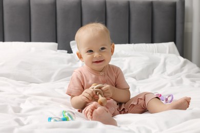 Photo of Cute little baby with rattles on bed indoors