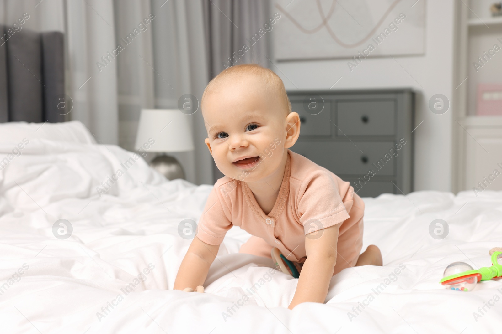 Photo of Cute little baby with rattle on bed indoors