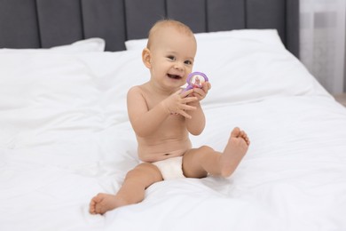 Photo of Cute little baby with rattle on bed indoors