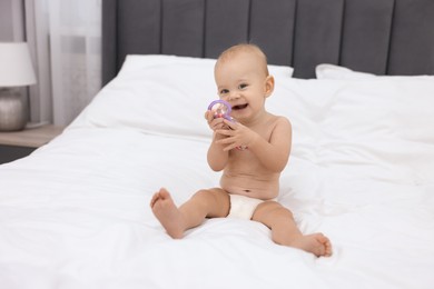 Photo of Cute little baby with rattle on bed indoors