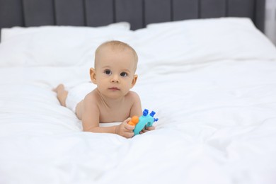 Photo of Cute little baby with rattle on bed indoors, space for text