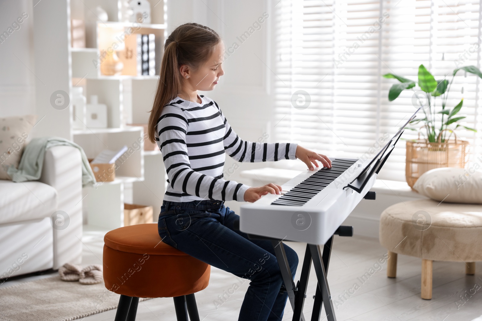 Photo of Cute girl playing synthesizer at home. Electronic musical instrument