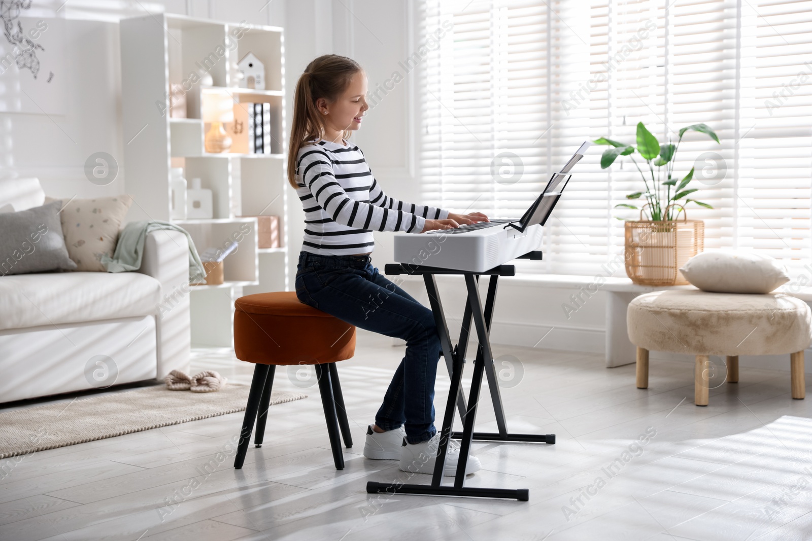 Photo of Cute girl playing synthesizer at home. Electronic musical instrument