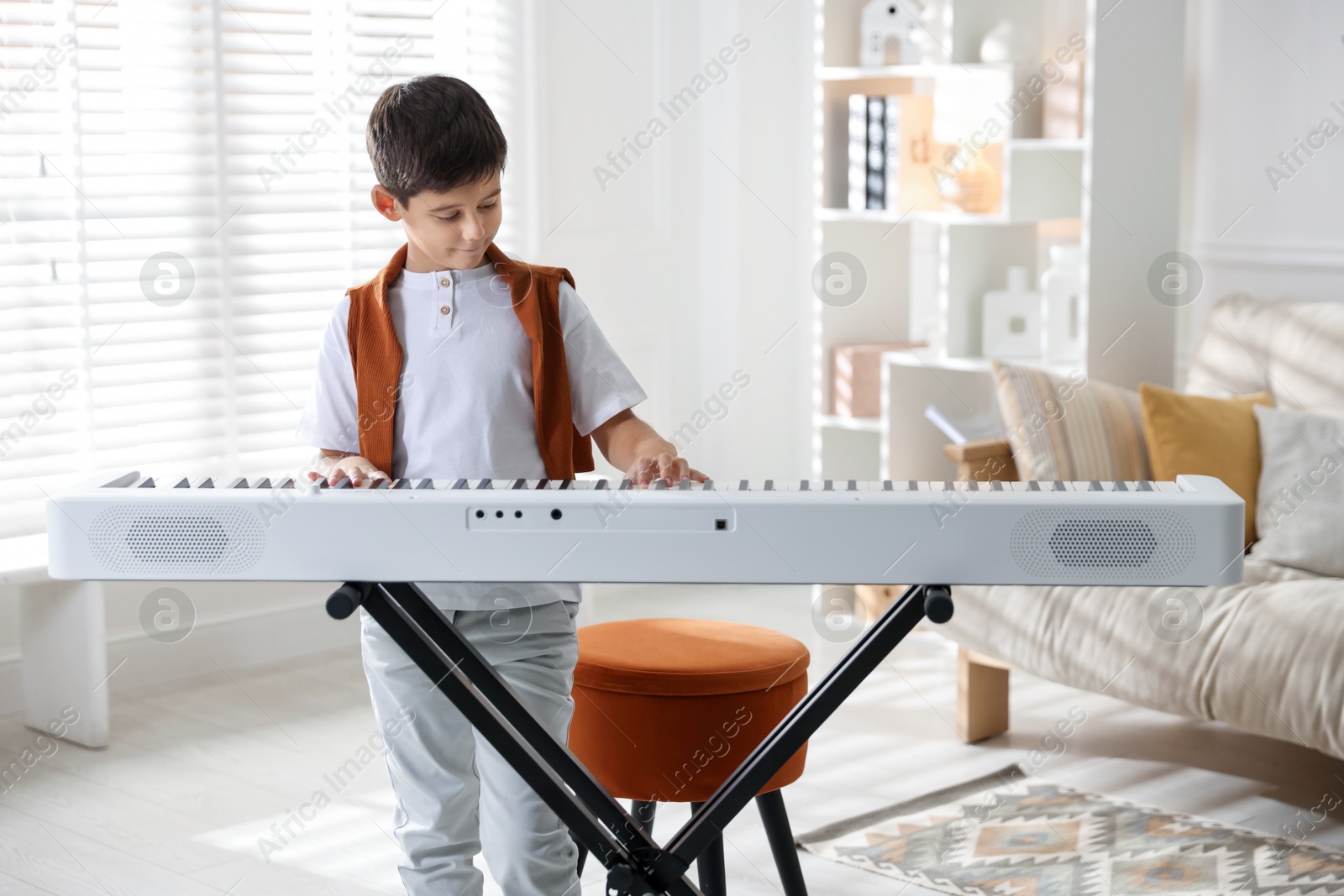 Photo of Cute boy playing synthesizer at home. Electronic musical instrument