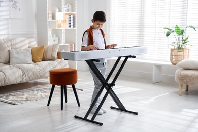 Photo of Cute boy playing synthesizer at home. Electronic musical instrument