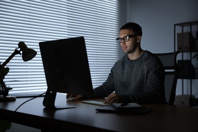 Photo of Programmer working on computer indoors at night