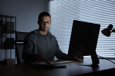 Photo of Programmer working on computer indoors at night