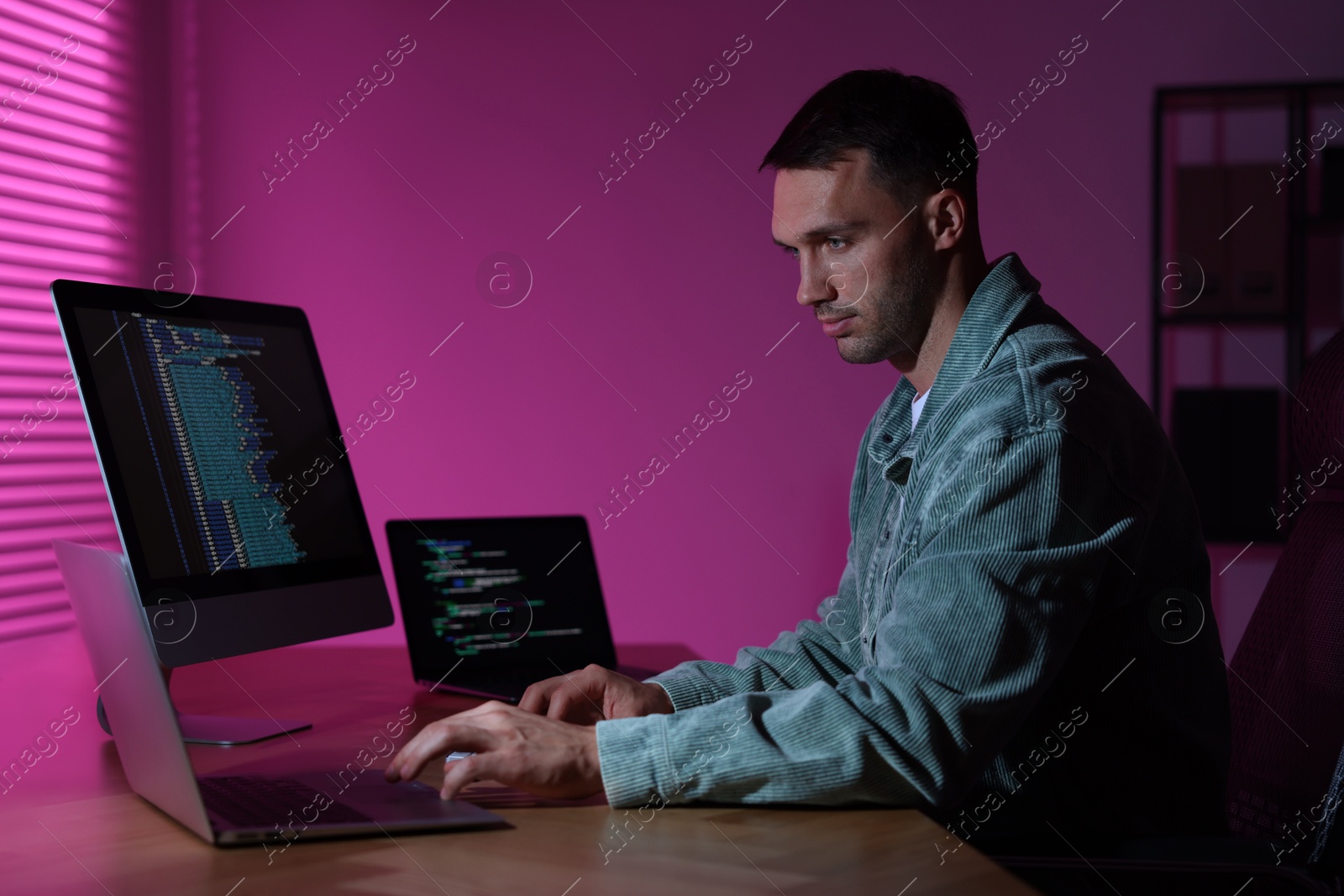 Photo of Programmer working on laptop indoors at night