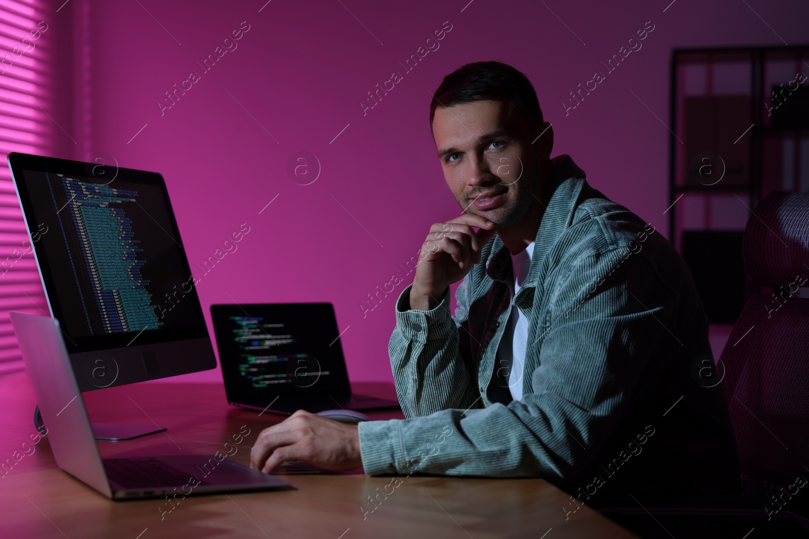 Photo of Programmer working on laptop indoors at night