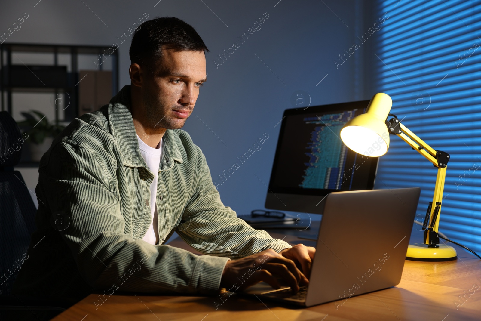 Photo of Programmer working on laptop indoors at night