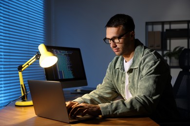 Photo of Programmer working on laptop indoors at night