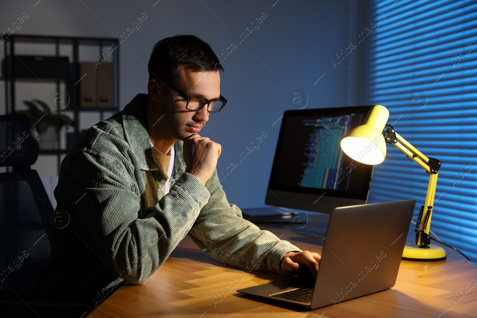 Photo of Programmer working on laptop indoors at night