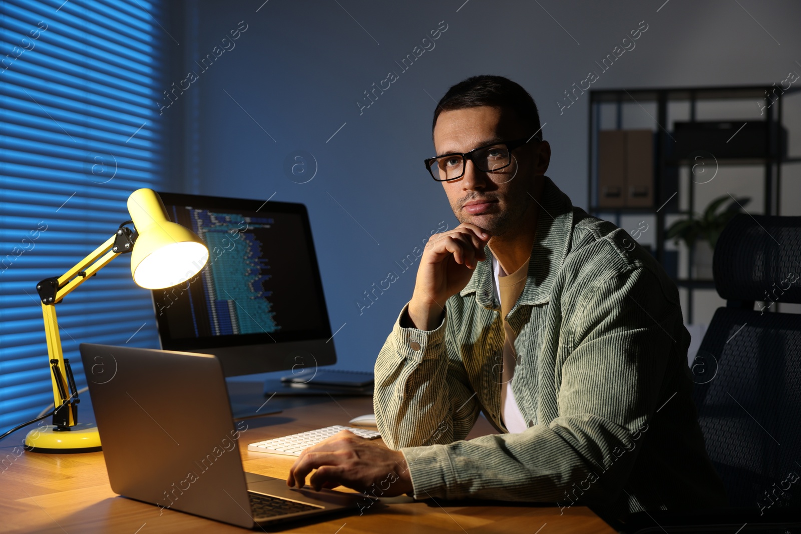 Photo of Programmer with laptop at wooden desk indoors