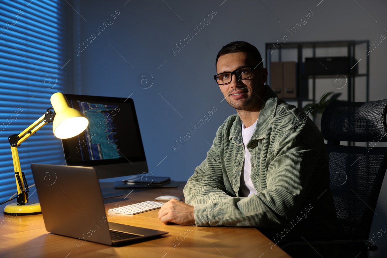 Photo of Programmer with laptop at wooden desk indoors