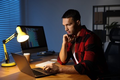 Programmer working on laptop indoors at night