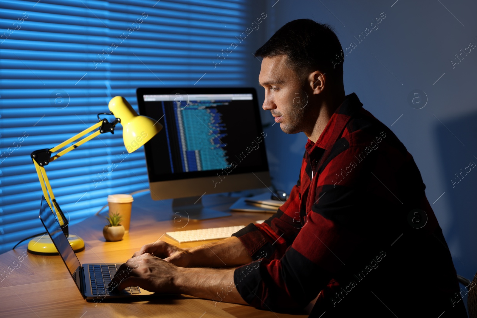 Photo of Programmer working on laptop indoors at night