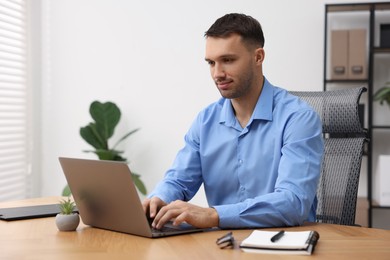 Photo of Programmer working on laptop at wooden desk indoors