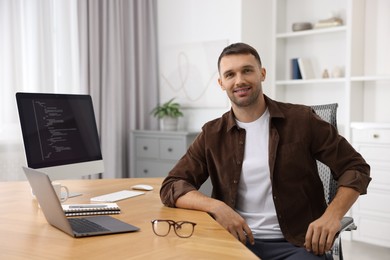 Photo of Portrait of programmer at wooden desk indoors