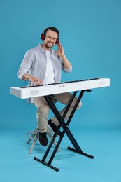 Photo of Smiling man playing synthesizer on light blue background