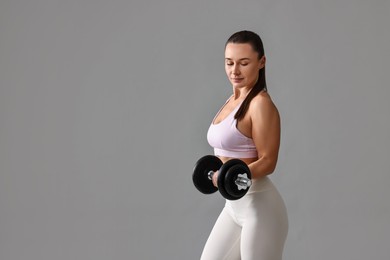 Photo of Woman in gym clothes exercising with barbell on grey background, space for text