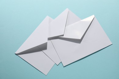 Photo of Paper envelopes on light blue background, flat lay. Mockup for design