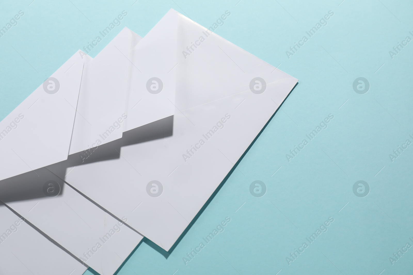 Photo of Paper envelopes on light blue background, closeup. Mockup for design