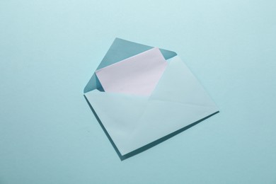 Paper envelope with letter on light blue background, above view. Mockup for design