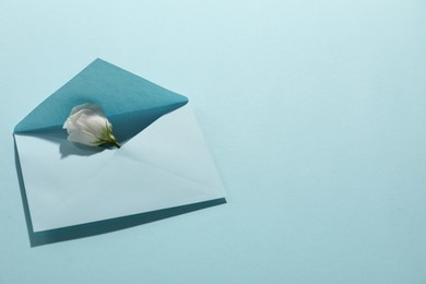 Paper envelope with flower on light blue background, above view. Mockup for design