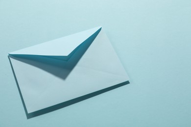 Paper envelope on light blue background, above view. Mockup for design