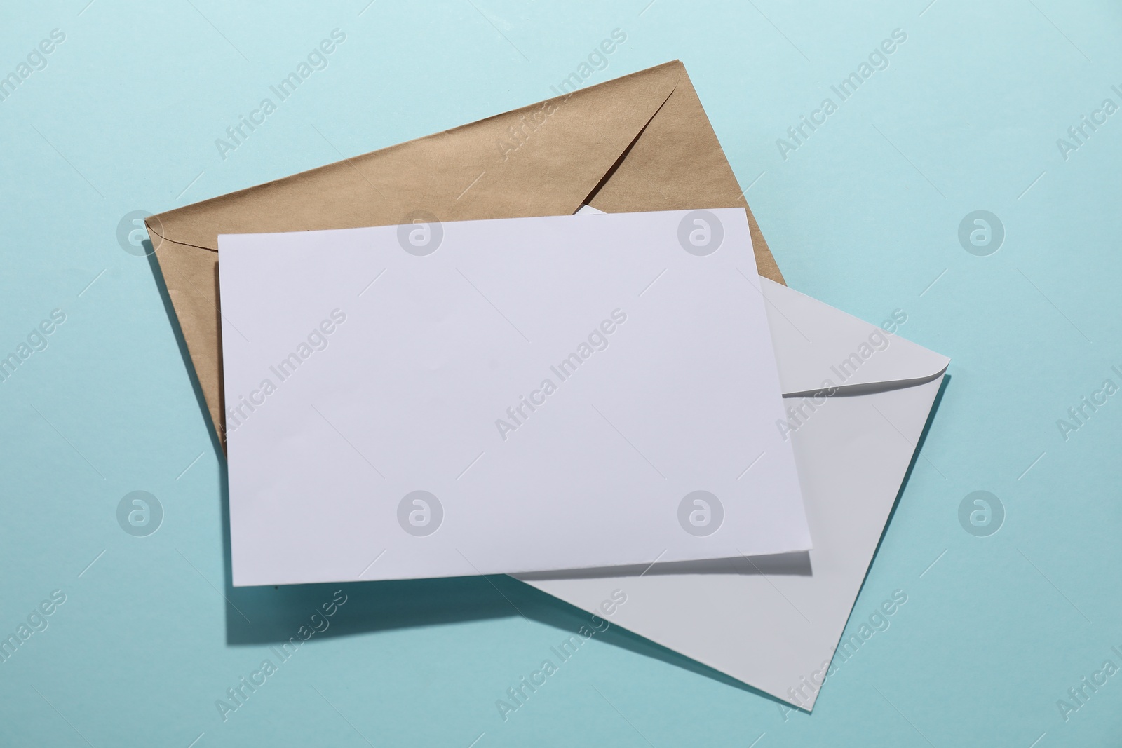 Photo of Paper envelopes with letter on light blue background, top view. Mockup for design