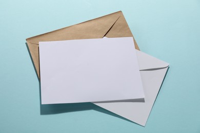 Paper envelopes with letter on light blue background, top view. Mockup for design