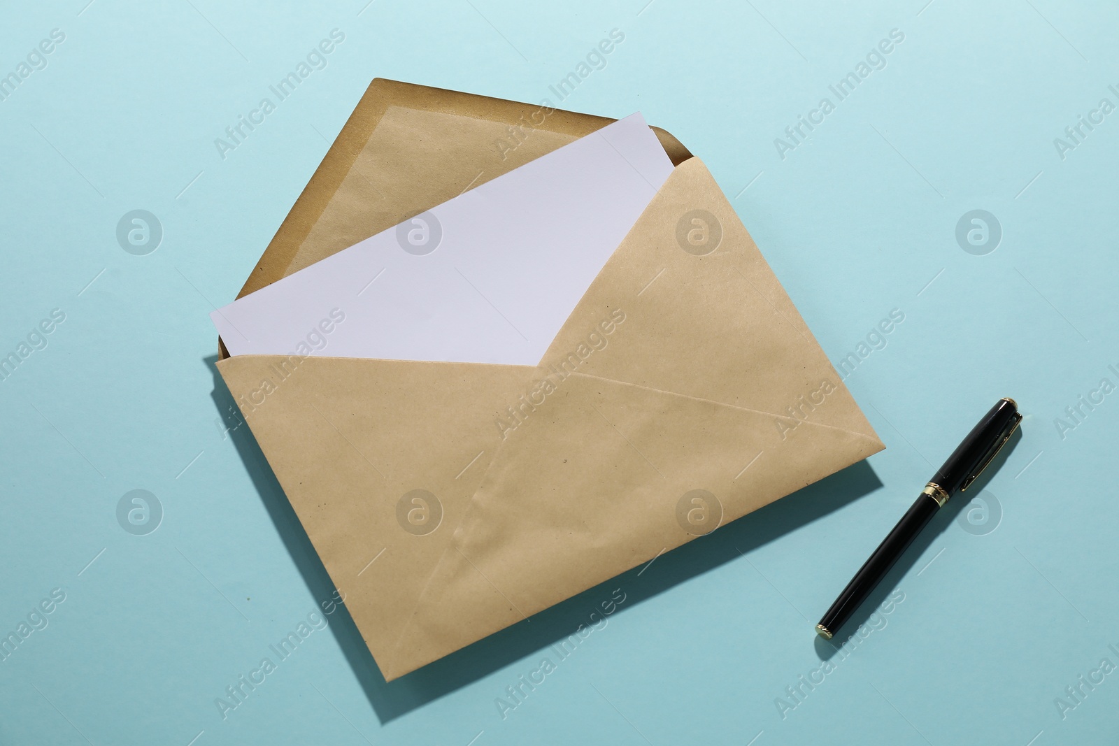 Photo of Kraft paper envelope with letter and pen on light blue background, top view. Mockup for design