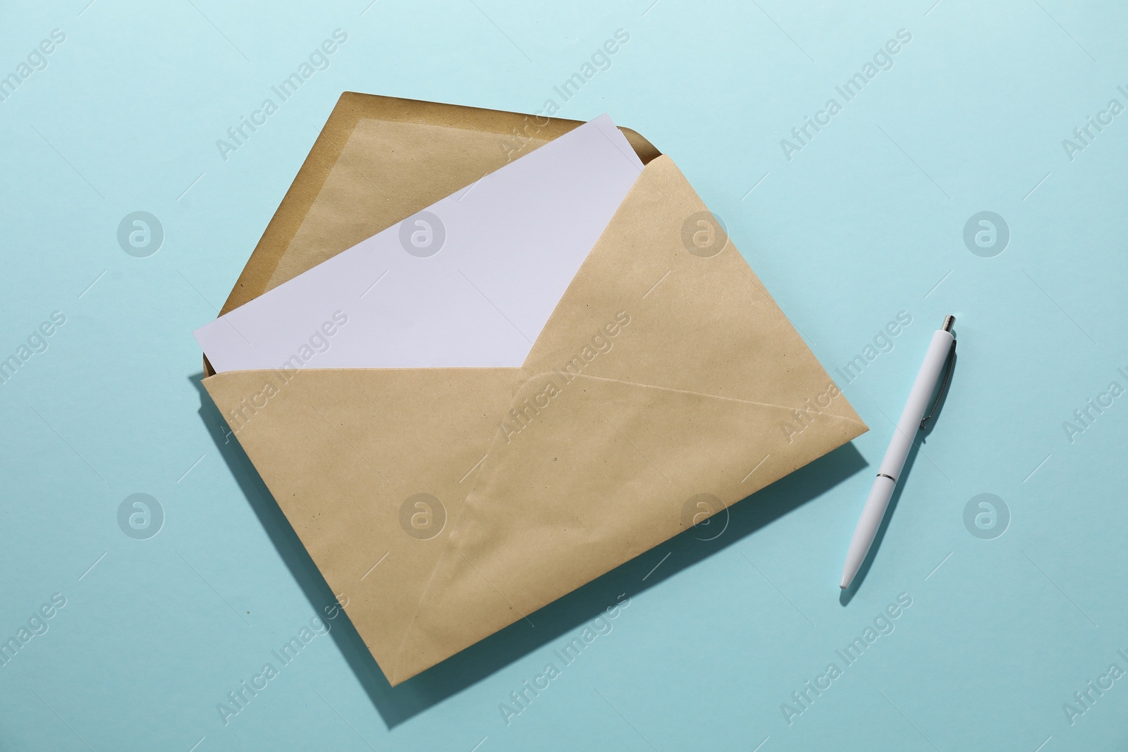 Photo of Kraft paper envelope with letter and pen on light blue background, top view. Mockup for design