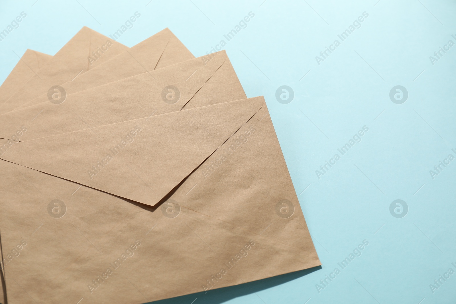 Photo of Kraft paper envelopes on light blue background, above view. Mockup for design