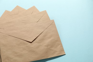 Kraft paper envelopes on light blue background, above view. Mockup for design