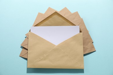 Kraft paper envelopes with letter on light blue background, top view. Mockup for design